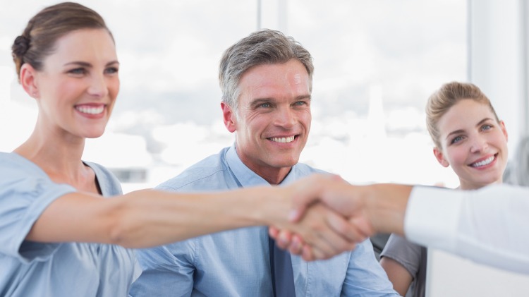 Young smiling woman shakes someone's hand