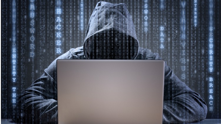 Hacker sits at computer with binary code in background