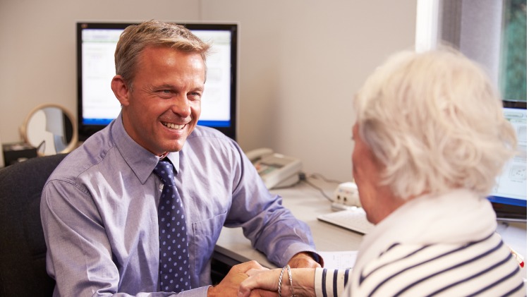 Male doctor shakes elderly female patient's hand