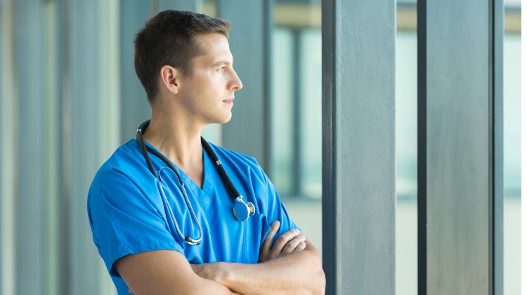 Young male doctor looks contemplative