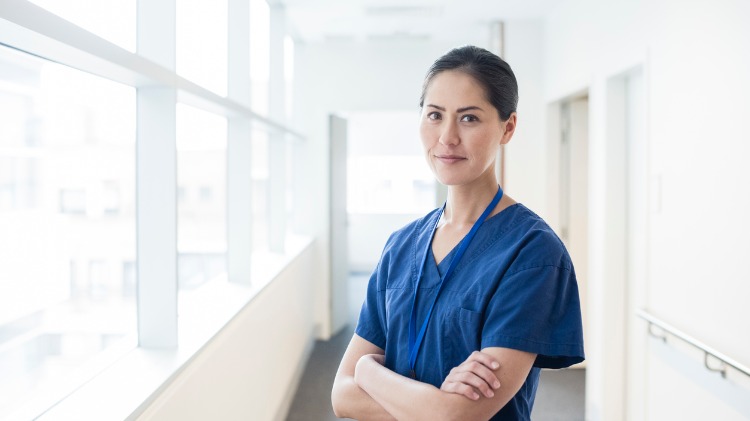 Female doctor standing in hospital corridor with folded arms