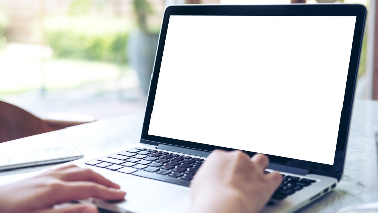 Hands typing on laptop with blank screen