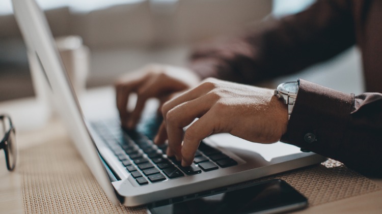 Hands typing on a laptop