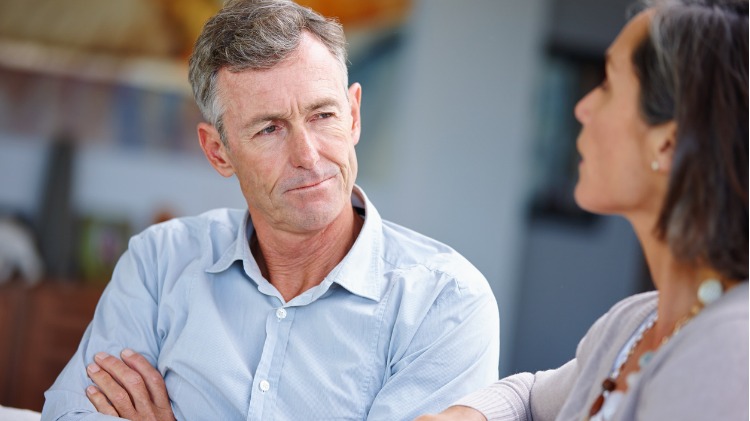 Man with crossed arms speaking to woman