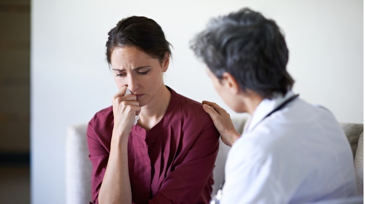 Doctor speaks to distressed female patient