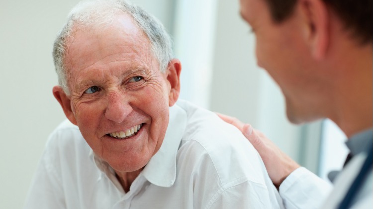 Male doctor speaks encouragingly to older man