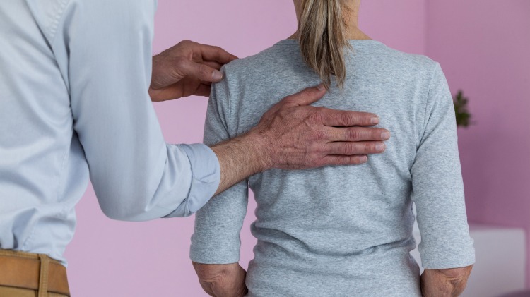 Uncomfortable female patient with hand on back