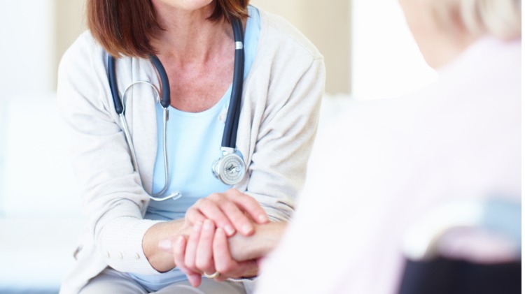 Female doctor holds patient's hand