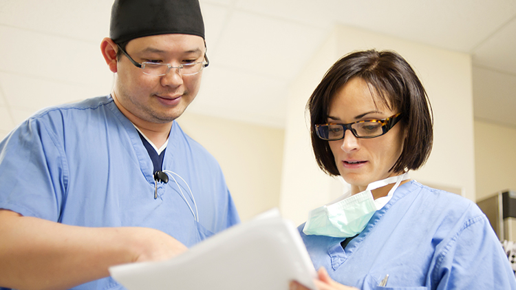 Two doctors in scrubs looking at paperwork