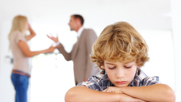 Child looks sad as parents fight in background