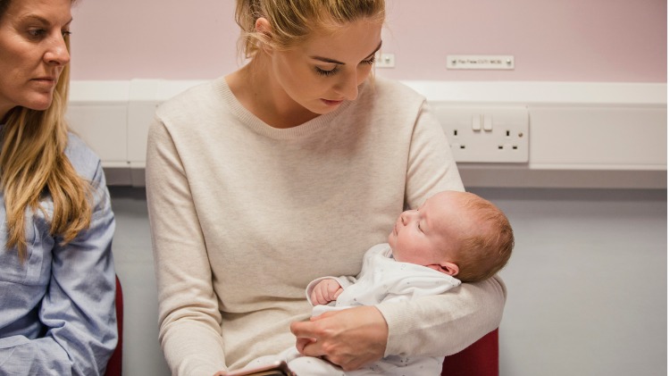 Mother sits in waiting room with baby