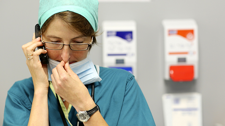Worried Dr in scrubs on phone
