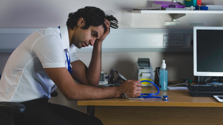 Worried young doctor looks exhausted