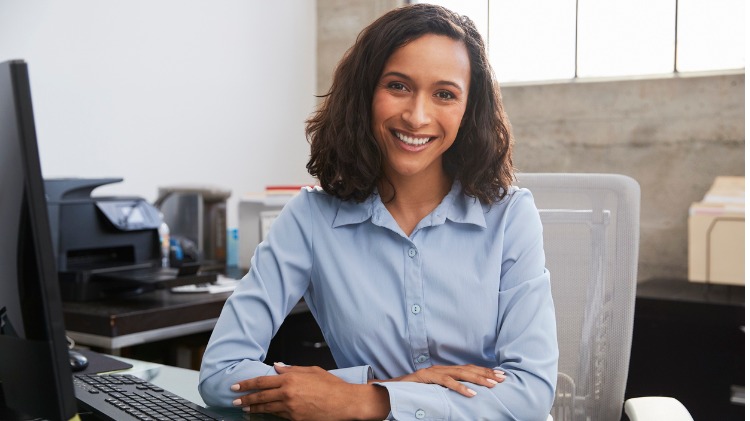 Young female doctor sits smiling at desk