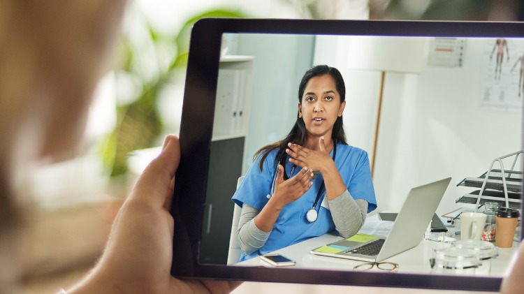 Person holding tablet with doctor on screen