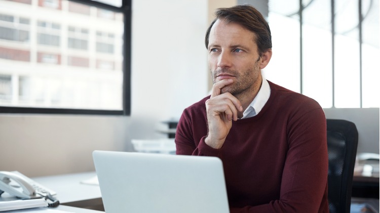 Man sitting at laptop with questioning look on his face
