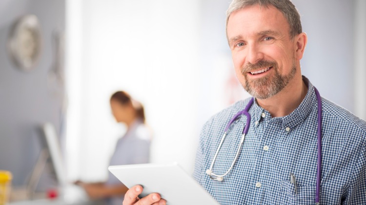 Friendly doctor looks up from tablet